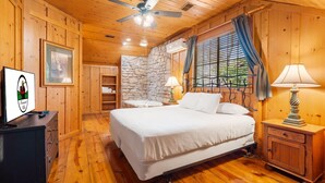 A wooden cabin bedroom with a bed, nightstand, dresser, and a stone wall.