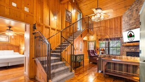 A wooden interior with a staircase, a fireplace, and a sofa.