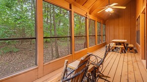 A wooden deck with large windows overlooking a forest.