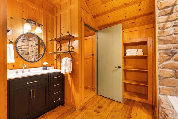 A wooden bathroom with a sink, mirror, and towel rack.