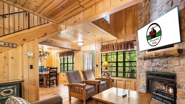 A wooden interior with a fireplace, a dining area, and a staircase.
