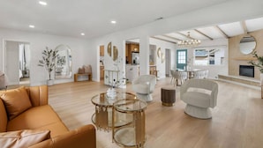 A spacious living area with a leather sofa, round glass coffee table, and modern chairs.