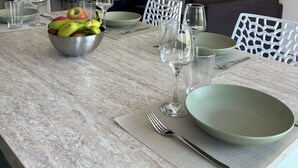 En spiseplads med et marmorbord, en skål med frugt samt matchende tallerkener og glas.