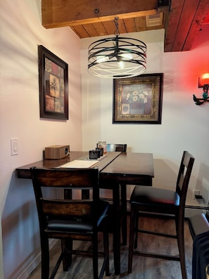 A dining area with a wooden table, four chairs, a chandelier, and two framed artworks on the wall. - Quiet North Pole Stay near Santa and FAI with Arctic Spa (North Pole)
