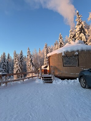 A snow-covered cabin with a wooden deck and a vehicle parked nearby. - Quiet North Pole Stay near Santa and FAI with Arctic Spa (North Pole)