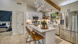 A modern kitchen with white cabinets, a stainless steel refrigerator, and a wooden island with bar stools.