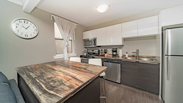 A modern kitchen with a wooden island, stainless steel appliances, and white cabinetry. - 12 Condo/King Bed/Close To  Attractions/Laundry (Niagara Falls)
