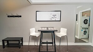 A modern room with a dining table and two chairs, a coat rack, and a framed picture on the wall. - 12 Condo/King Bed/Close To  Attractions/Laundry (Niagara Falls)