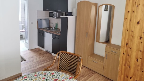 Una cucina compatta con elettrodomestici moderni, un'area pranzo con una sedia e un armadio.