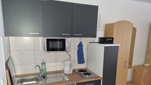 Una cucina compatta con forno a microonde, macchina del caffè e lavello.