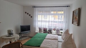 Una camera da letto con un letto, televisione, un tavolino con una macchina del caffè e una finestra con tende.