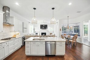 Enjoy cooking in the spacious kitchen with a large island, gas range, and ample counter space, complemented by a dining area with a window overlooking the outdoors.