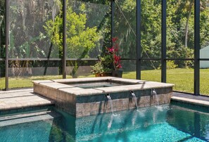 Relax by the pool surrounded by lush greenery and a soothing water feature.