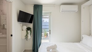 A bedroom with a bed, a TV mounted on the wall, an air conditioning unit, a view of the sea, and a balcony with potted plants. - Ocean Park 3BDR+2BA Hot Tub Terrace @Riviera Villa (San Juan)