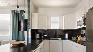A modern kitchen with white cabinets, a black countertop, and stainless steel appliances. - Ocean Park 3BDR+2BA Hot Tub Terrace @Riviera Villa (San Juan)