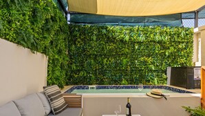 Zona de piscina con área de descanso, piscina y pared cubierta de vegetación.