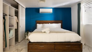 Un dormitorio moderno con una cama grande, un armario y un equipo de aire acondicionado integrado.