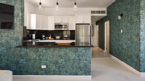 Una cocina moderna con armarios blancos, electrodomésticos de acero inoxidable y encimera negra.
