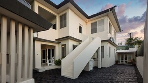 Una casa moderna de dos pisos con una escalera central, un porche cubierto y un camino de ladrillo.