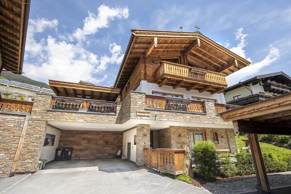 A multi-story building with a stone facade, wooden balconies, and a garage entrance. - Chalet With Sauna and Natural Pool (Neukirchen am Grossvenediger)