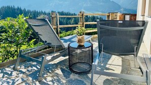 A terrace with two lounge chairs, a small round table, and a potted plant. - Chalet With Sauna and Natural Pool (Neukirchen am Grossvenediger)