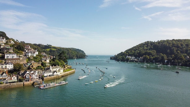 A coastal town with a marina filled with boats, surrounded by hills and residential buildings. - Elegant Couples' Escape in Dartmouth (Dartmouth)