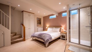 A bedroom with a bed, a nightstand, a window, a shower, and a staircase. - Elegant Couples' Escape in Dartmouth (Dartmouth)