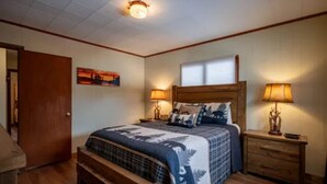 A bedroom with a wooden bed, two bedside tables with lamps, a window, and a door.