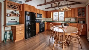 A kitchen with wooden cabinets, a black refrigerator, and a dining table with chairs.