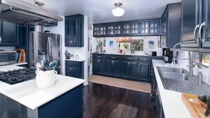 A modern kitchen with dark cabinets, stainless steel appliances, and a central island.