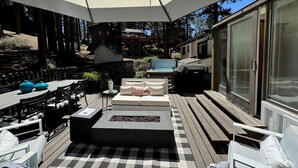 An outdoor patio with a checkered floor, a fire pit, and a sofa with pillows.