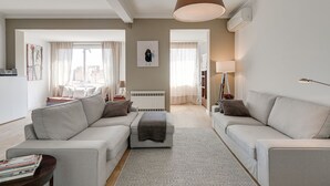 A modern living room with a sofa set, a coffee table, and a lamp. There is a radiator under the window and a picture on the wall. - RAMBLA CATALUNYA SKY (Barcelona)