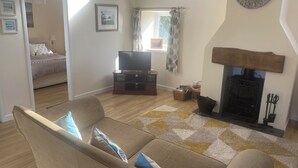 Una sala de estar con sofá, televisión, chimenea y una cama en la habitación contigua.