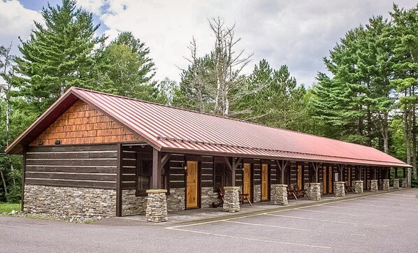 A log cabin-style building with a red roof, stone foundation, and wooden doors.