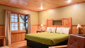 A wooden-paneled bedroom with a bed, two bedside tables, and a chair. - Club 51 (Mercer)