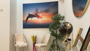 A room with a glass table, two chairs, a globe, a framed picture, and a painting of dolphins. - One Lux Stay Near Antwerp Central Grande Deluxe 3 Bedroom Suite (Antwerp)