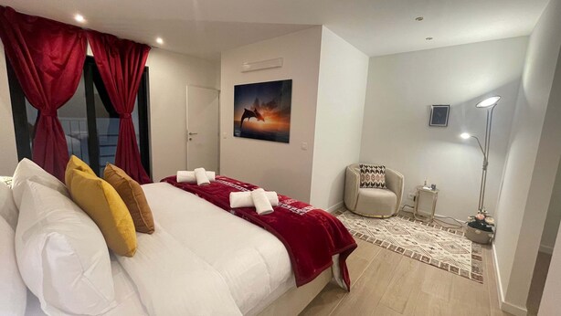 A hotel room with a bed, a chair, a floor lamp, and a painting on the wall. - One Lux Stay Near Antwerp Central Grande Deluxe 3 Bedroom Suite (Antwerp)