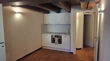 A compact kitchen with white cabinets, a built-in oven, and a herringbone-patterned floor.