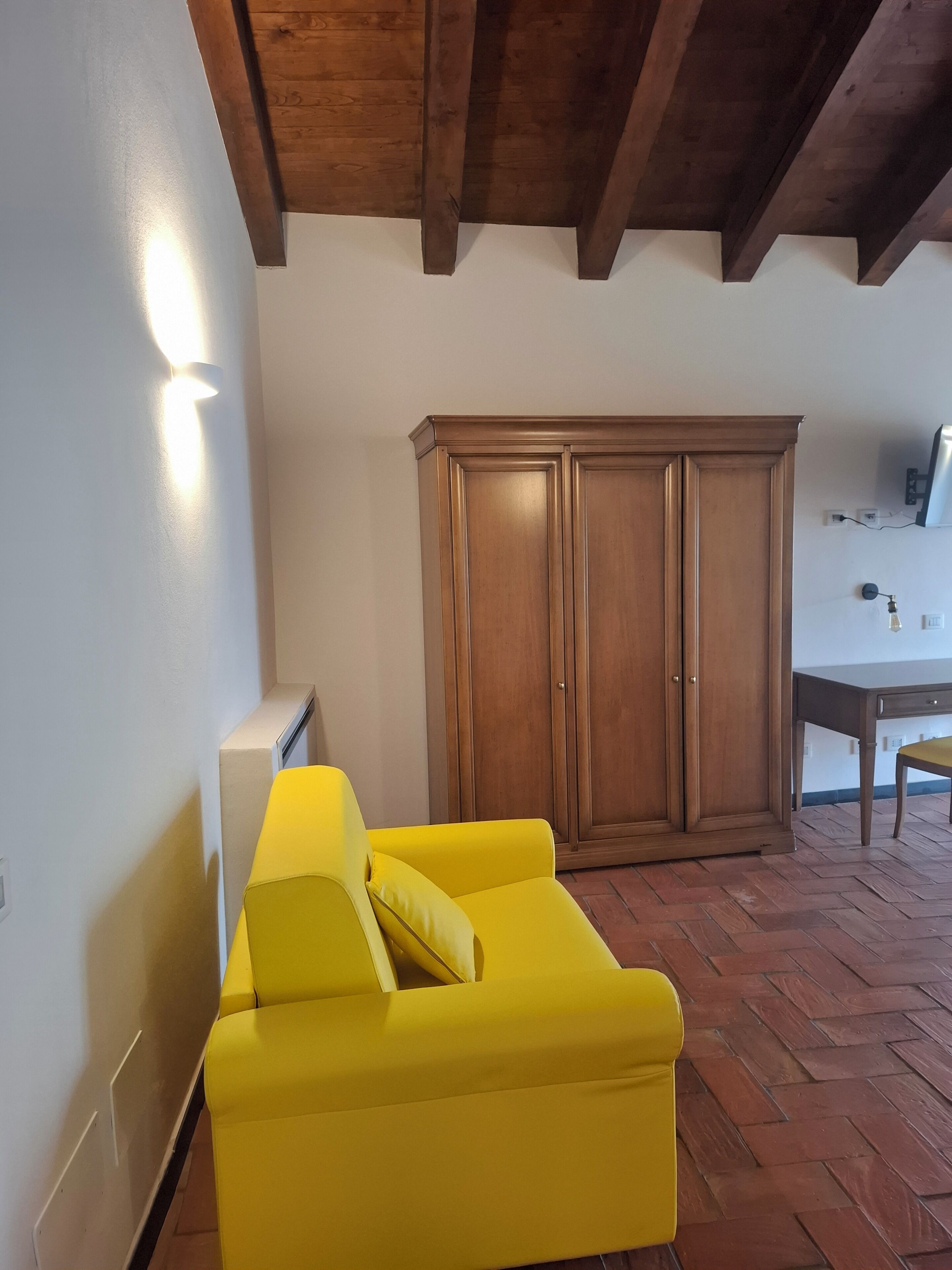 Ein Zimmer mit einem gelben Sofa, einem Holzschrank und einem Tisch mit einer Lampe.