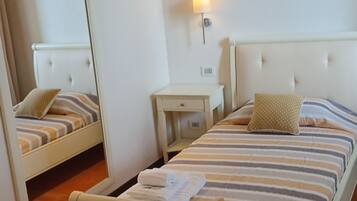 Ein Hotelzimmer mit Bett, Schreibtisch, Stuhl, Nachttisch und Spiegel.