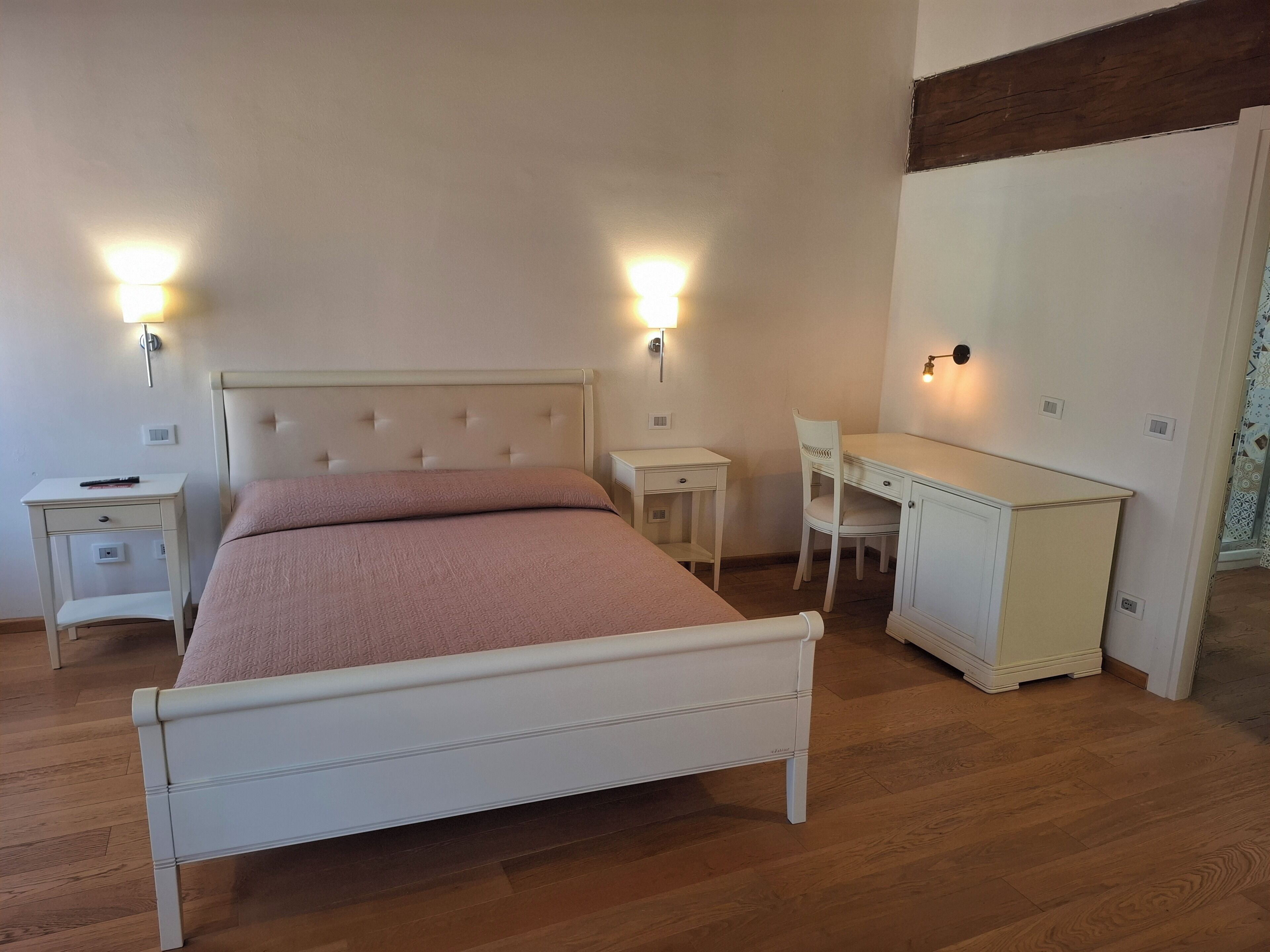 A bedroom with a bed, bedside tables, a desk, and a chair.