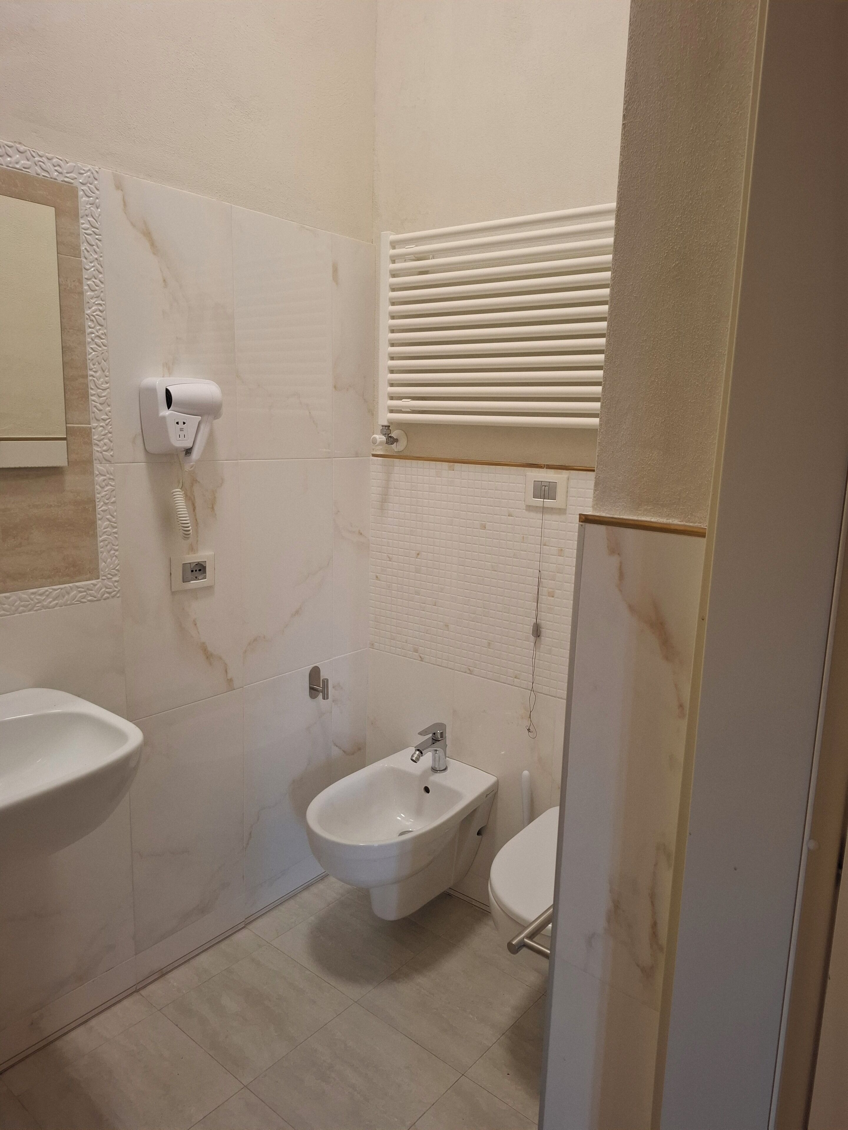 Een badkamer met een wastafel op een voetstuk, een bidet en een spiegel.