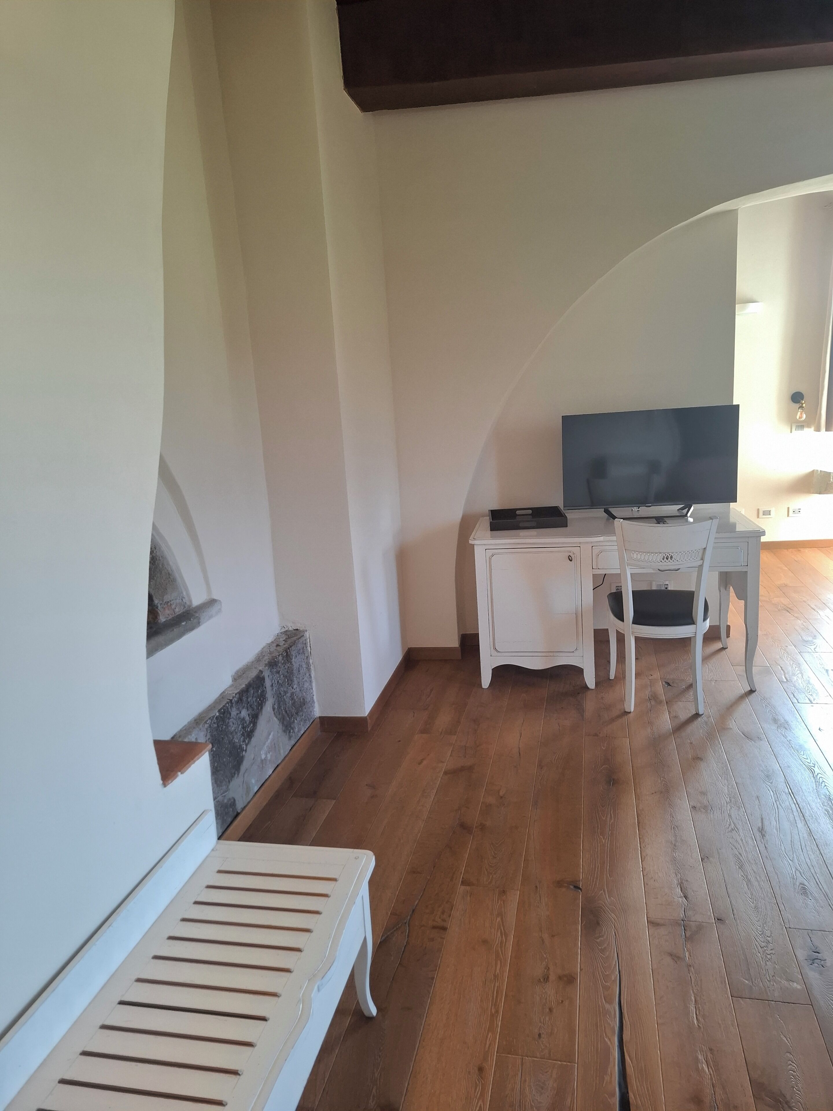 Una habitación con piso de madera, muebles blancos, chimenea y televisor.