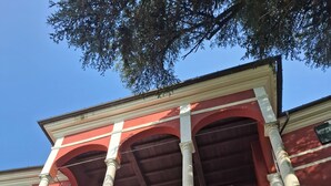 A building with a red facade, white trim, and multiple windows with metal bars. - Albergo Palazzo Costa (Beverino)