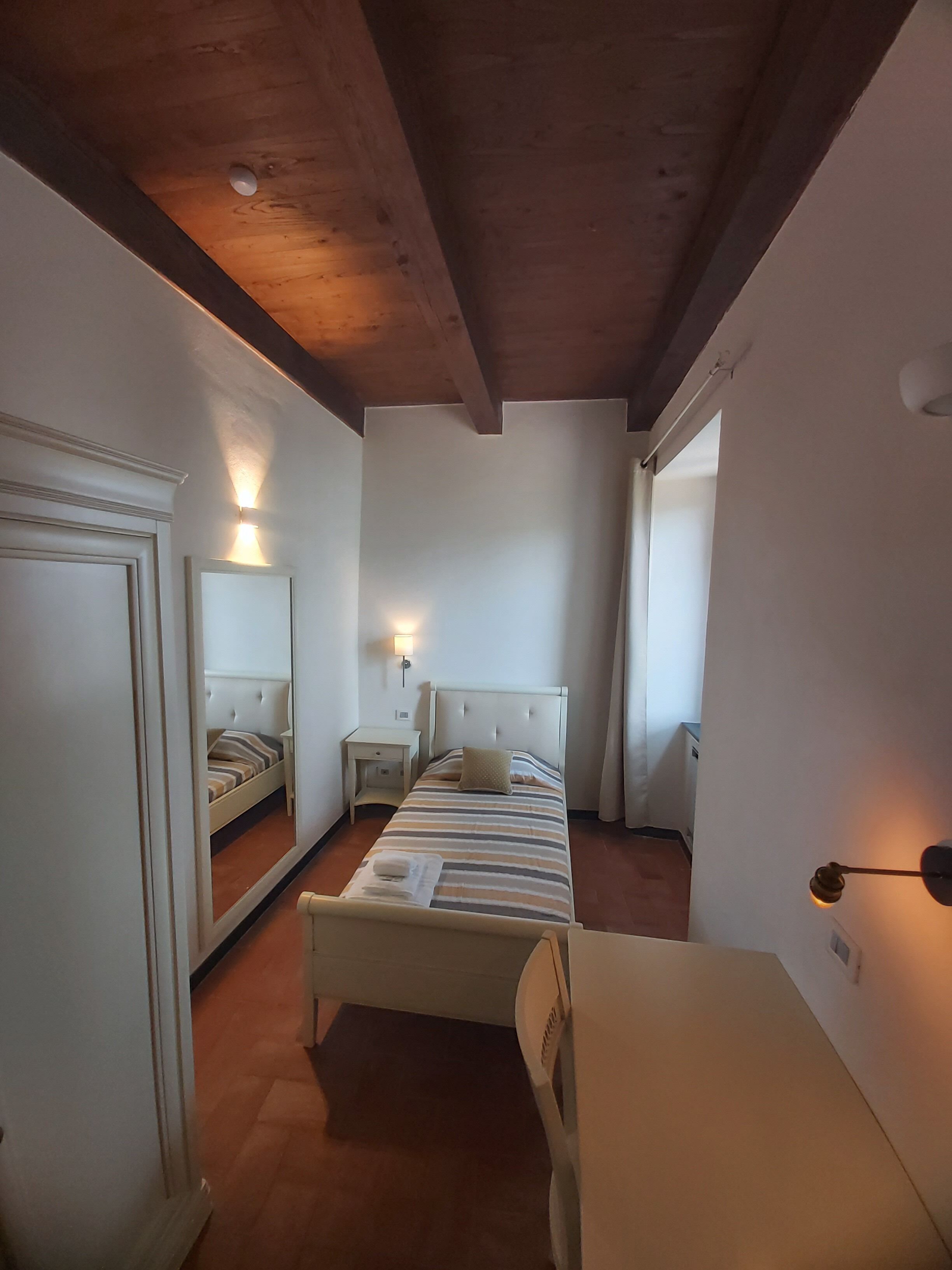 Une chambre à coucher avec un lit, des tables de chevet, un miroir et une armoire.