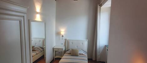 Une chambre à coucher avec un lit, des tables de chevet, un miroir et une armoire.