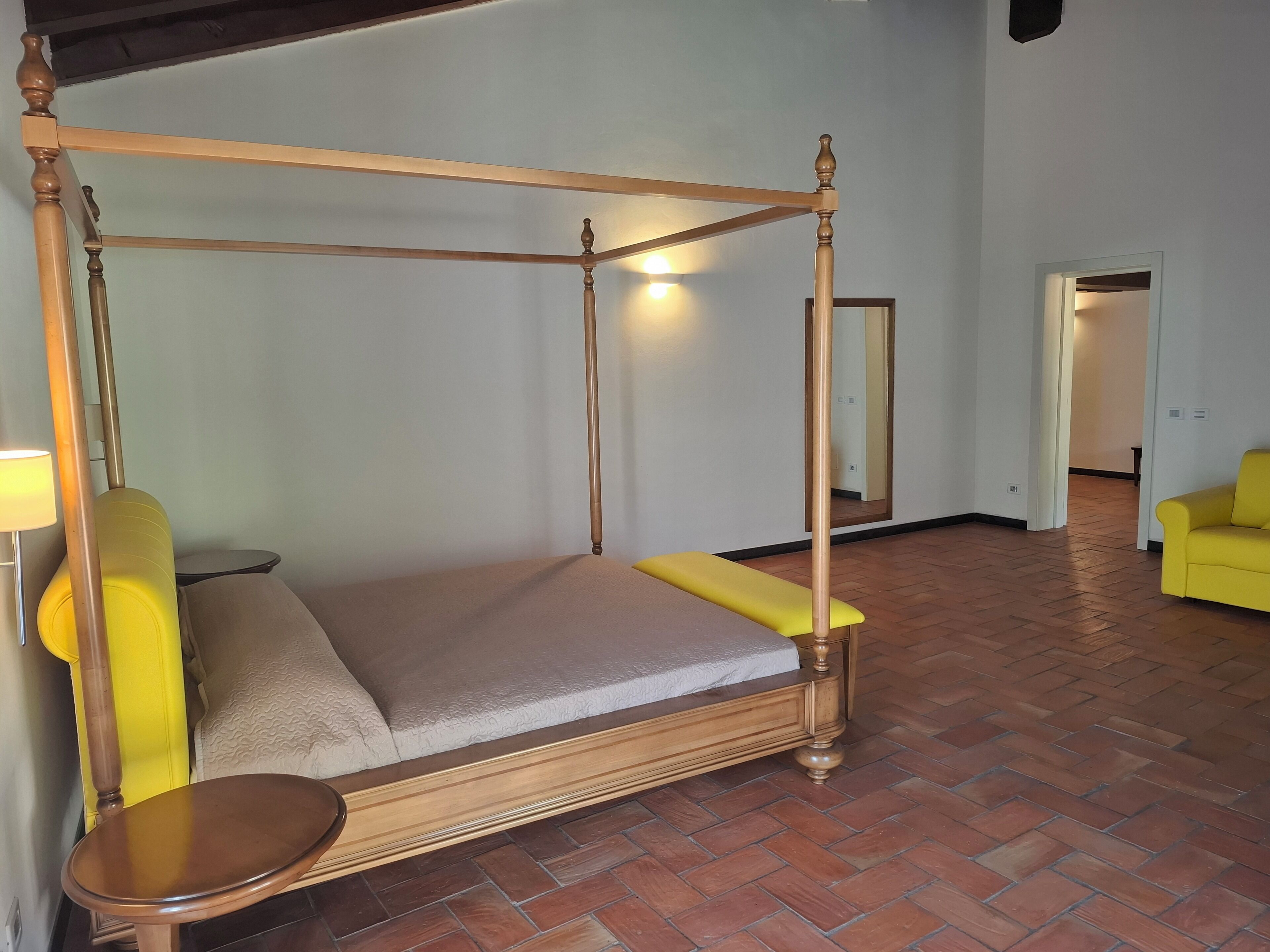 Una cama con dosel de estructura de madera y un banco al pie.