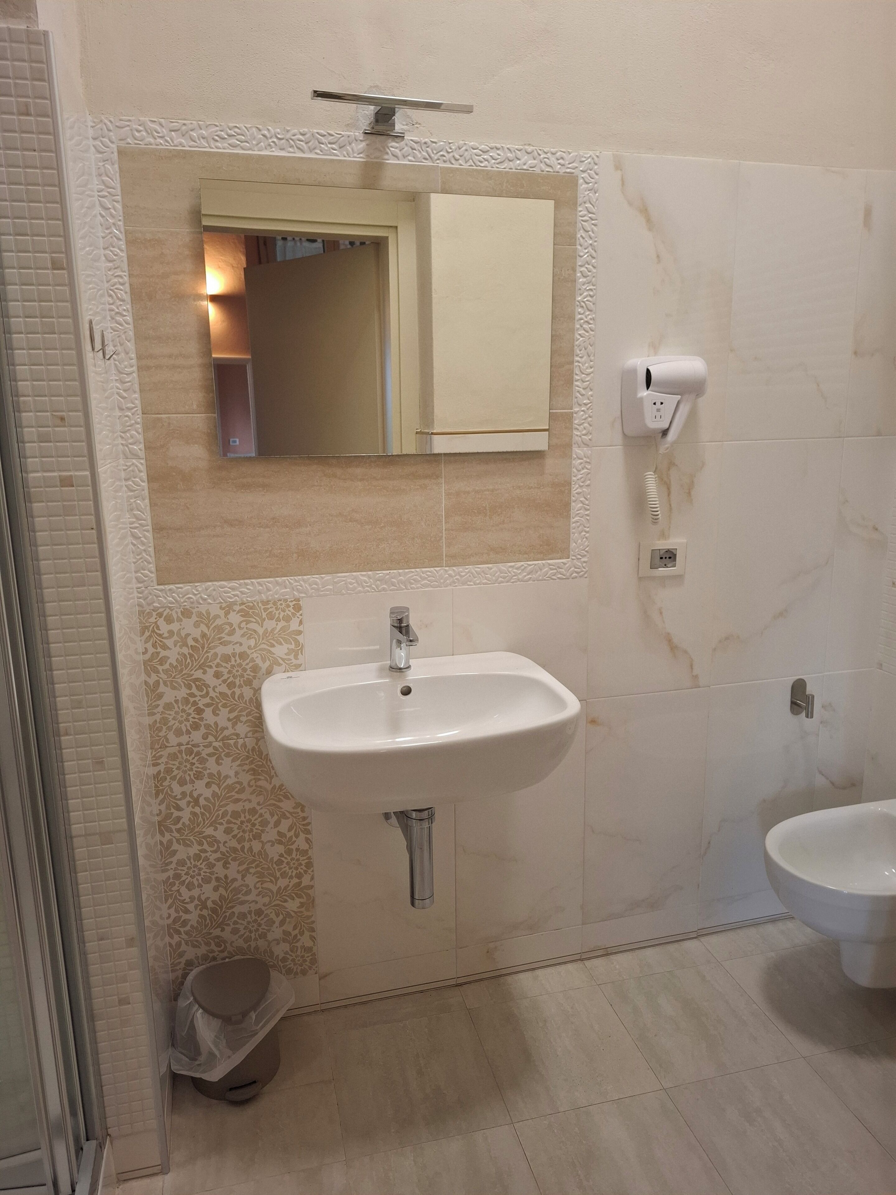 Un baño con lavamanos, espejo, inodoro y ducha.