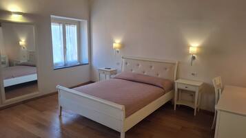 Un dormitorio con cama, mesitas de noche, un espejo y una ventana.