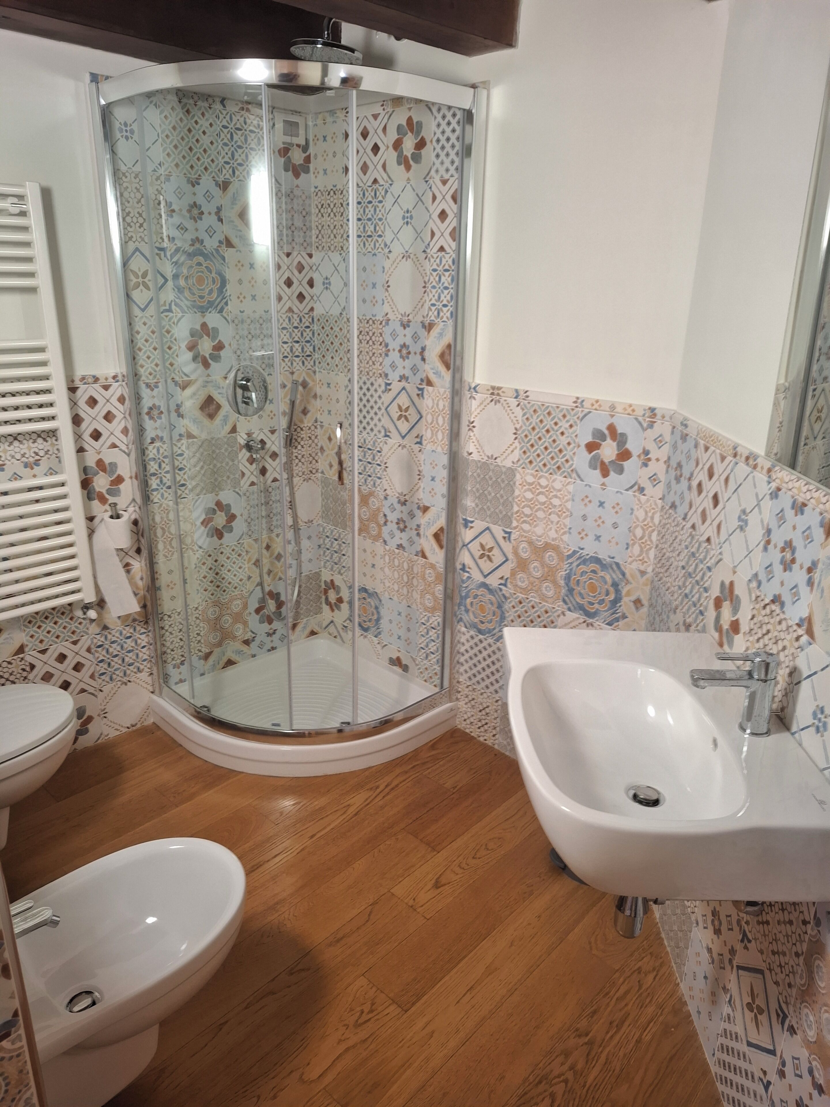 Un baño con cabina de ducha de vidrio, lavamanos e inodoro.